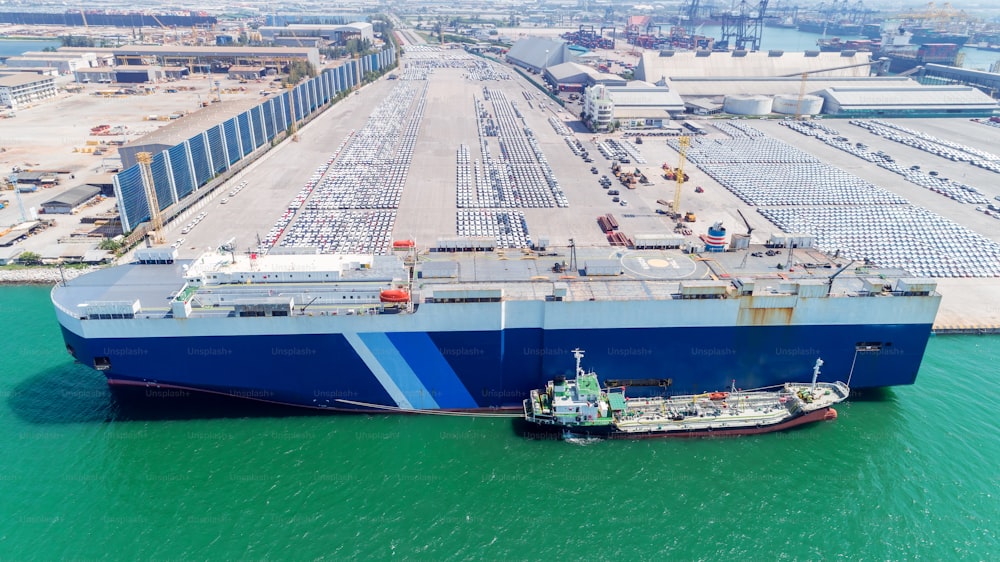 Vue aérienne Navire porteur de véhicule naviguant sur le parking dans le port maritime ou la fabrication en attente d’expédition exportée vers le monde entier.
