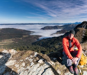 männlicher Wanderer auf dem Gipfel des Chli Aubrig in den Schweizer Alpen mit tollem Blick auf die Landschaft dahinter