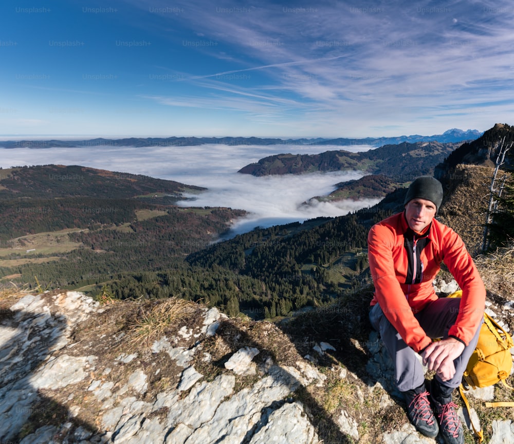 escursionista maschio sulla vetta del Chli Aubrig nelle Alpi svizzere con una splendida vista sul paesaggio alle sue spalle