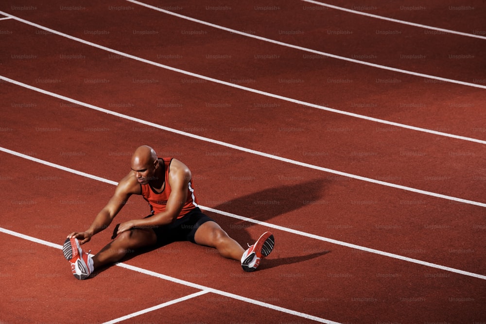 Atleta afroamericano che si allunga sulla pista da corsa