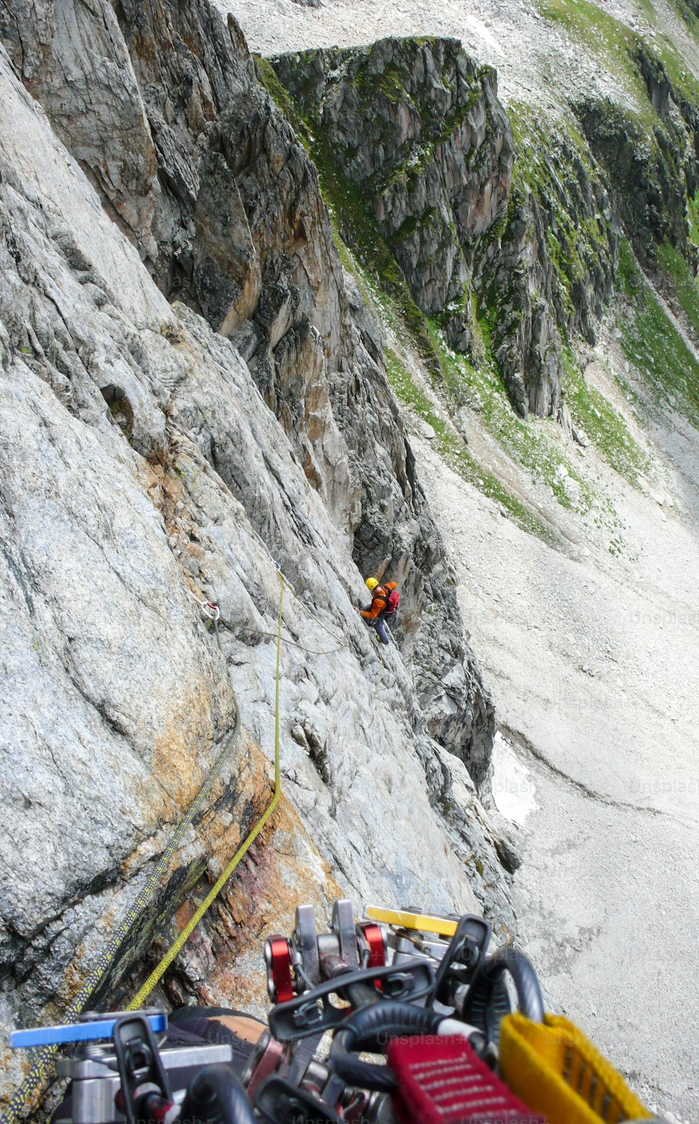 rock climber on a hard alpine route on Pizzo Forcella in the Alps of Switzerland placing mobile protection