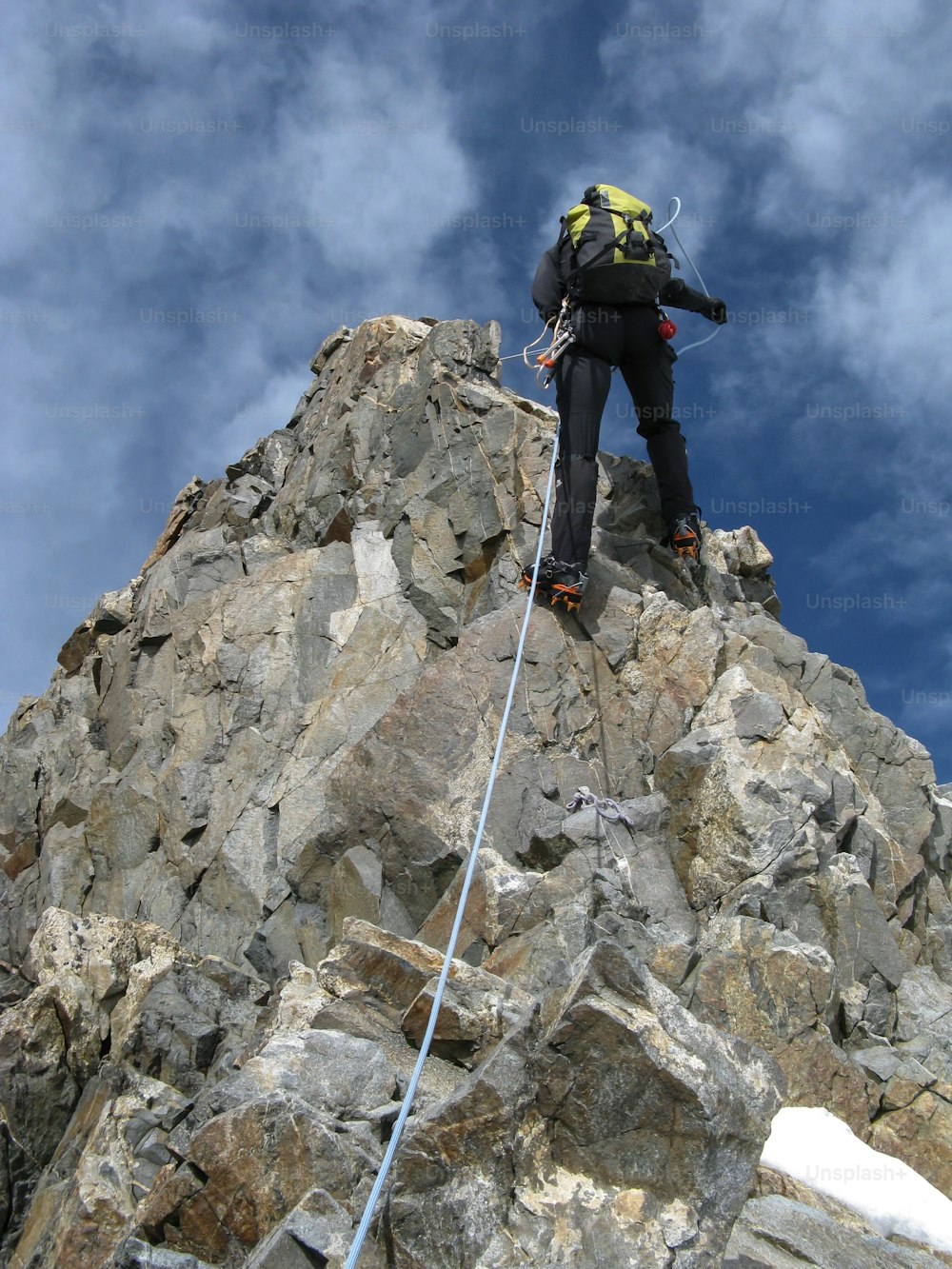 mountain climber rappelling on the long and narrow Biancograt Ridge in the Alps of Switzerland heading to the high remote mountain peak of Piz Bernina