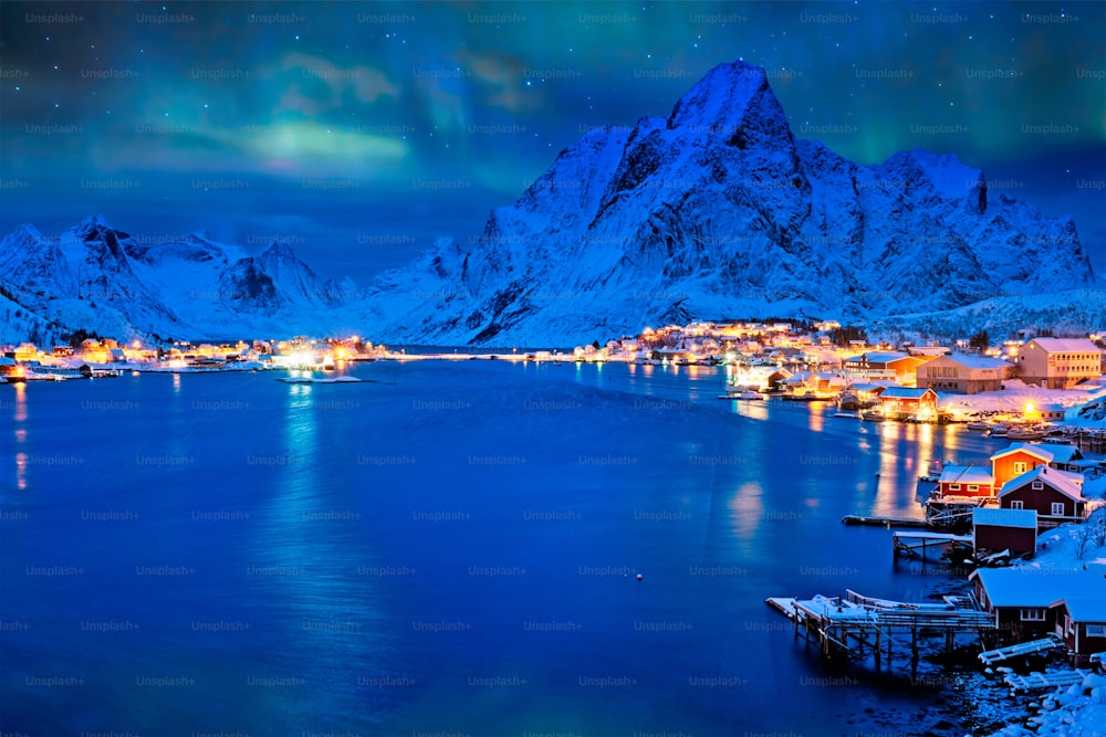 El pueblo de Reine iluminado por la noche con auroras boreales. Islas Lofoten, Noruega
