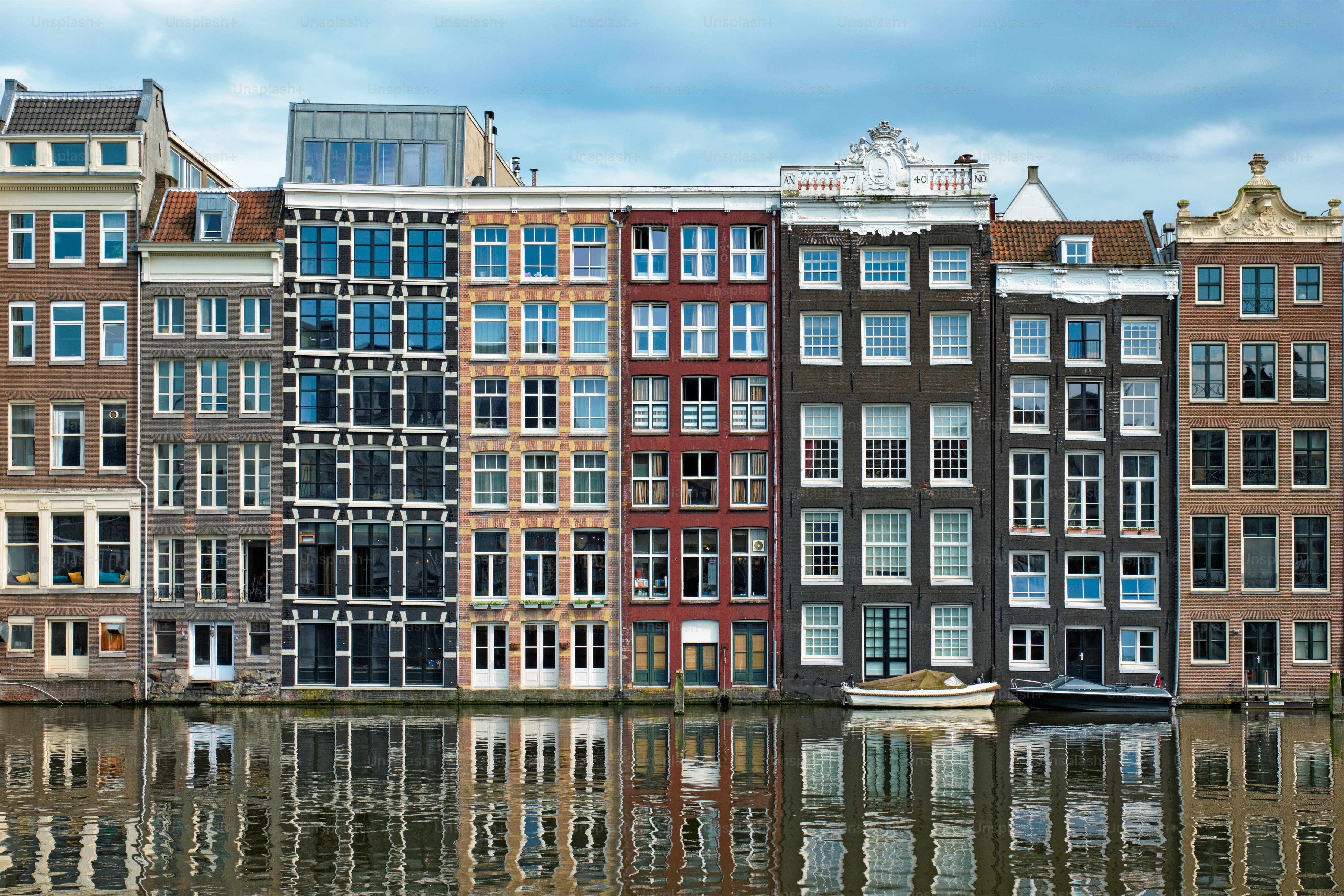 Row of typical houses and boat on Amsterdam canal Damrak with reflection. Amsterdam, Netherlands