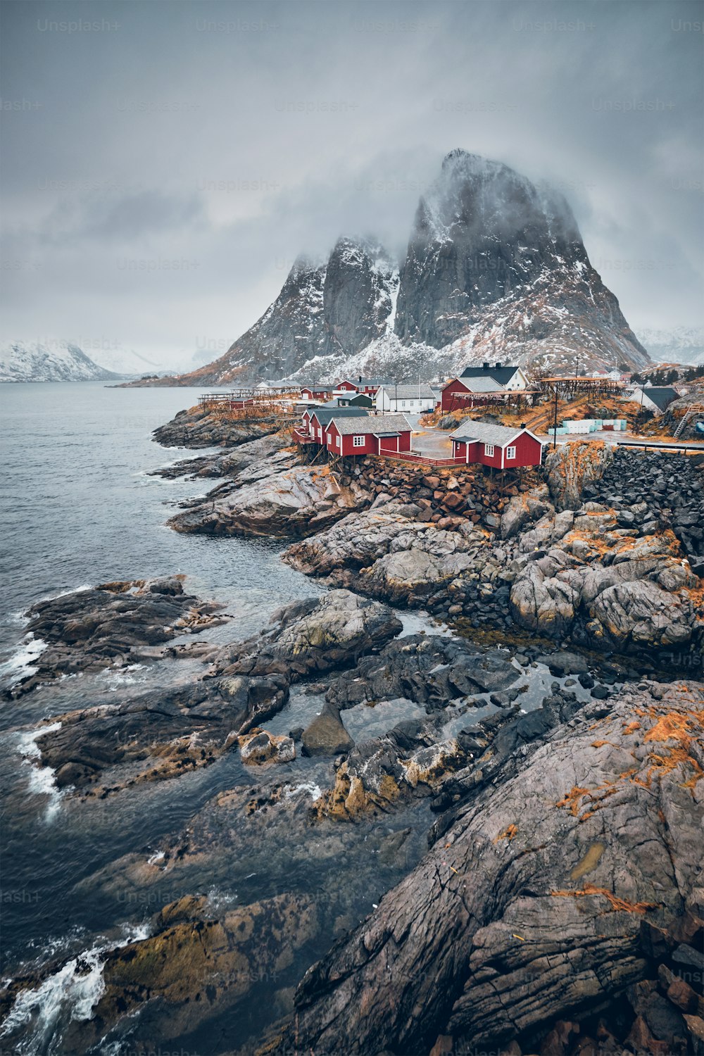 Famosa atracción turística del pueblo pesquero de Hamnoy en las islas Lofoten, Noruega, con casas rorbu rojas. Con la nieve cayendo en invierno