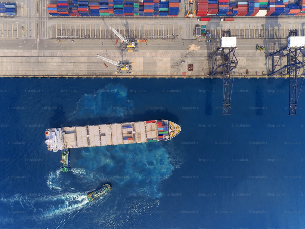 Aerial top view Tug boat drag container ship at sea port to crane bridge for load container, logistics import export, shipping or transportation concept background.