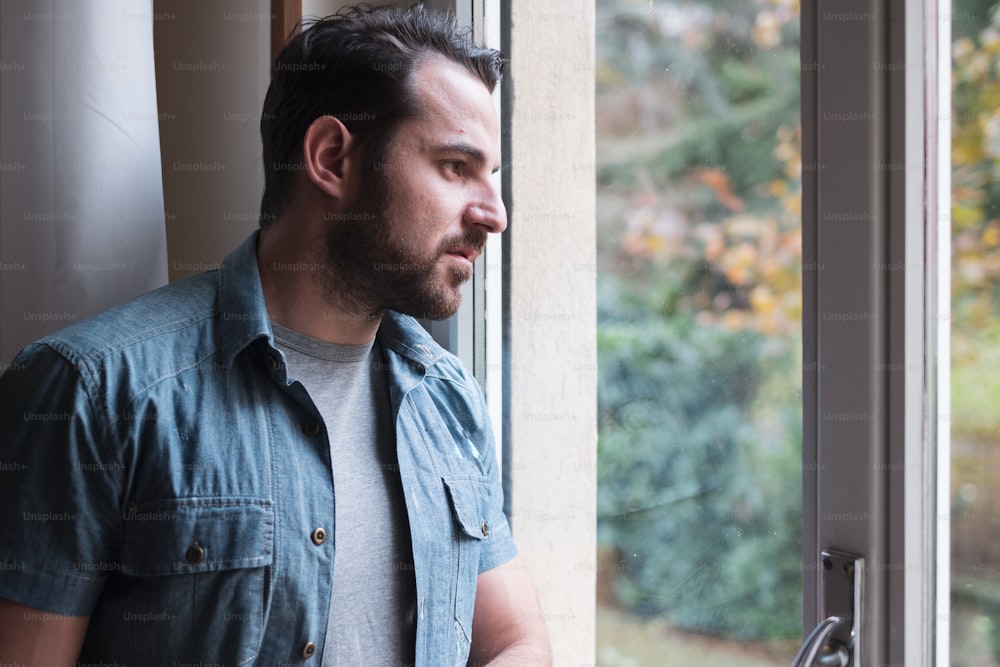 Worried man looking thoughtful out of window