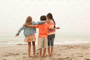 a group of young children standing on top of a sandy beach