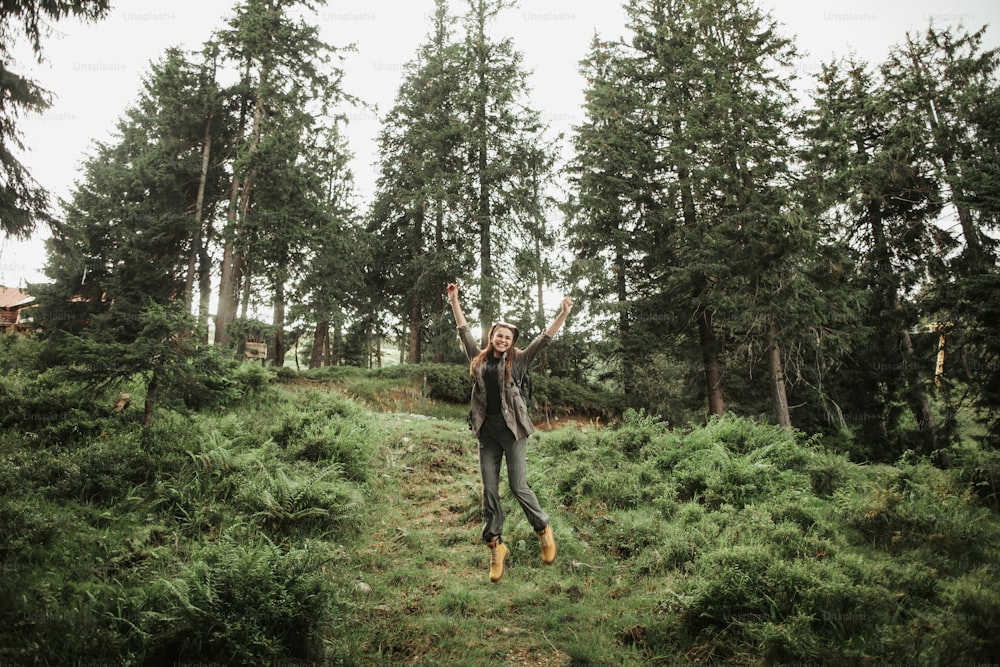 I can fly. Full length portrait of excited young lady expressing happiness in beautiful coniferous wood