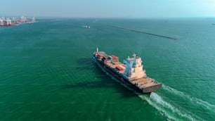 Nave portacontainer con vista aerea che va al porto marittimo per scaricare il contenitore per l'importazione, l'esportazione, la spedizione o il concetto di trasporto.