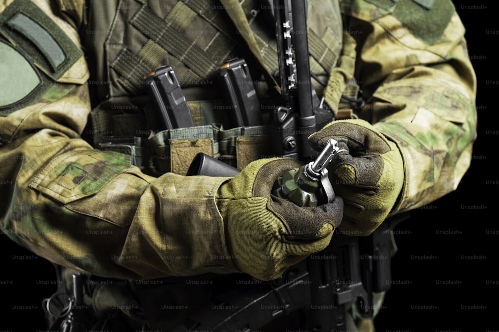 Soldado em munição de combate total puxa um cheque de uma granada. Mídia mista