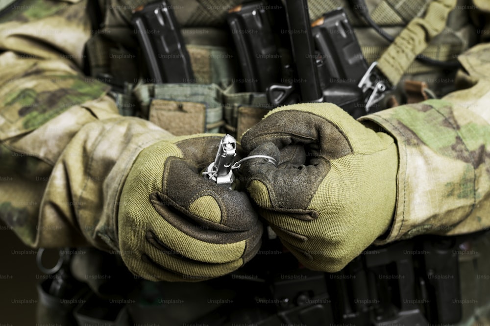 Soldat in voller Kampfmunition zieht einen Scheck aus einer Granate. Mischtechnik