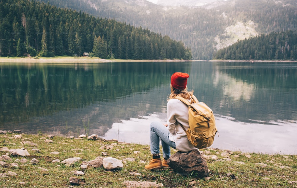 Ragazza escursionista solitaria che si riposa accanto a un lago di montagna.