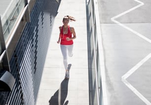 Una donna in un top rosso sta correndo lungo un marciapiede