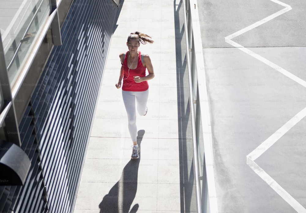 Uma mulher de capota vermelha está correndo por uma calçada