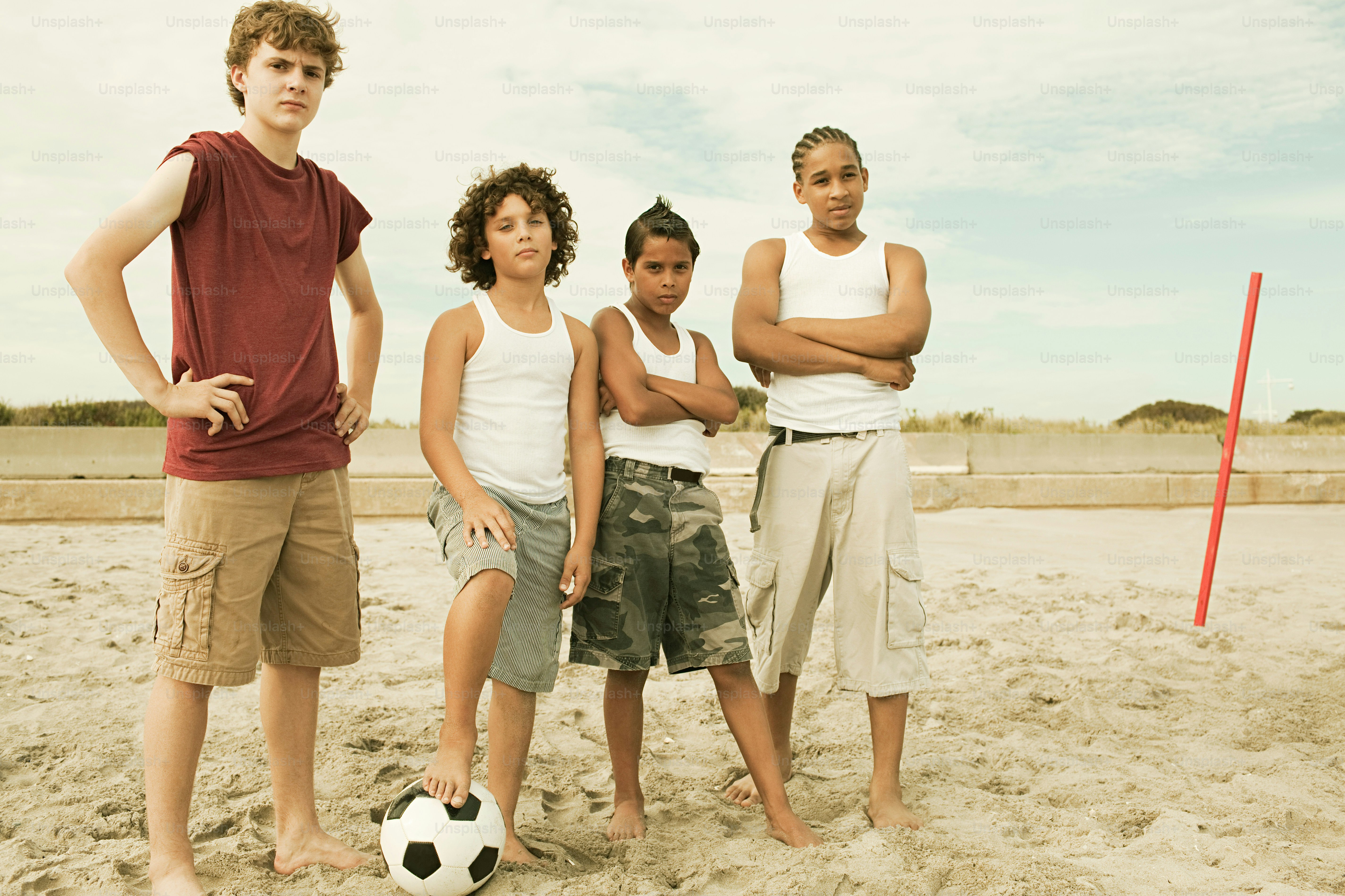 A group of young people standing on top of a sandy beach photo – Pre ...