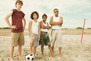 um grupo de jovens em pé em cima de uma praia de areia