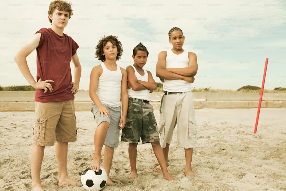 a group of young people standing on top of a sandy beach