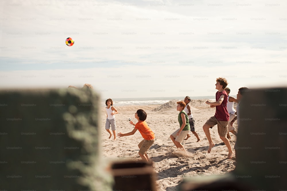 a group of people playing with a ball on the beach
