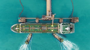 Tug boats drag Oil ship tanker park to port for transfer crude oil to oil refinery.