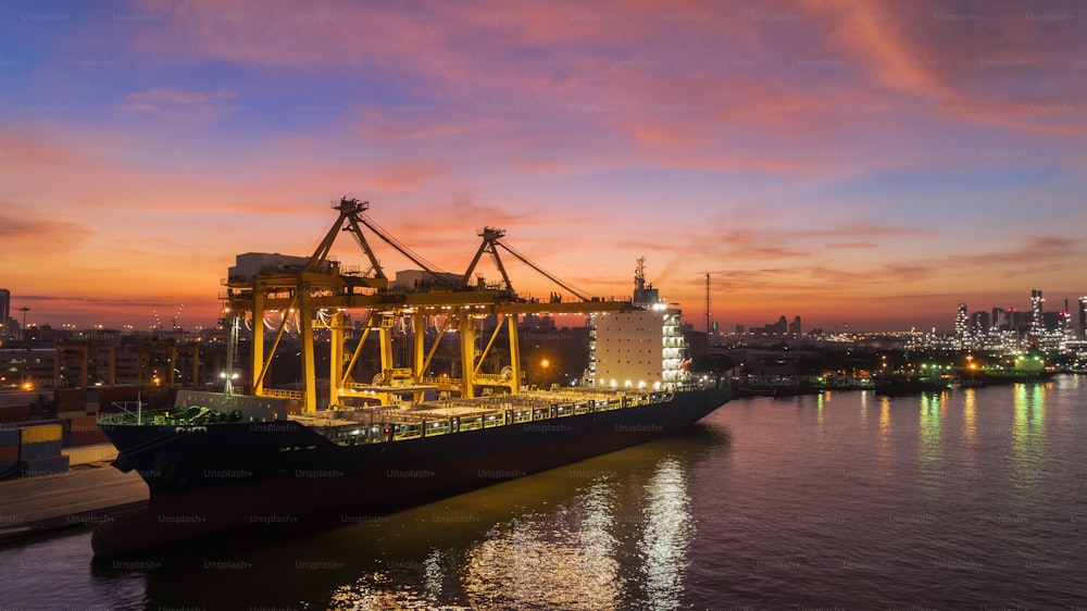輸出入または輸送コンセプトの背景に美しい空を持つ海港と作業クレーンブリッジローディングコンテナへのコンテナ船。
