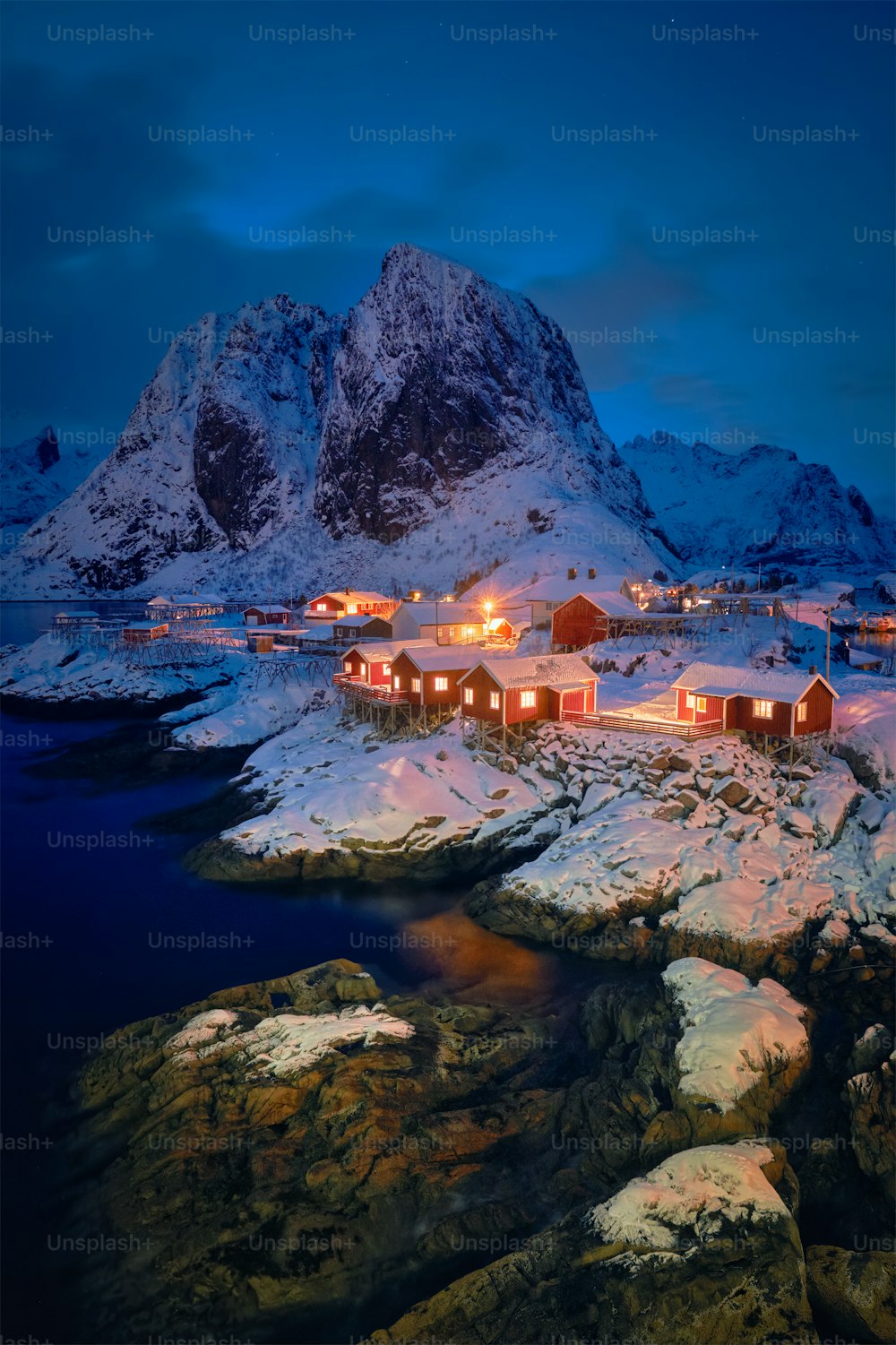 Célèbre attraction touristique Hamnoy village de pêcheurs sur les îles Lofoten, Norvège avec des maisons rorbu rouges en hiver neige illuminée le soir