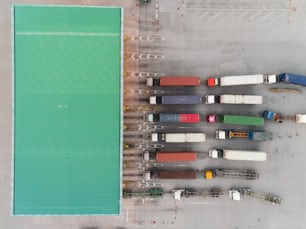 Aerial view Truck carry container ship waiting to sea port for unloading container for logistics  import  export or transportation concept background.