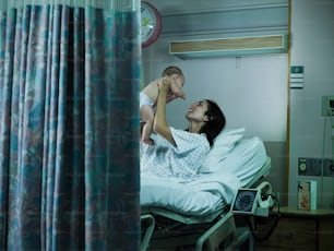 病院のベッドに横たわって赤ん坊を抱える女性