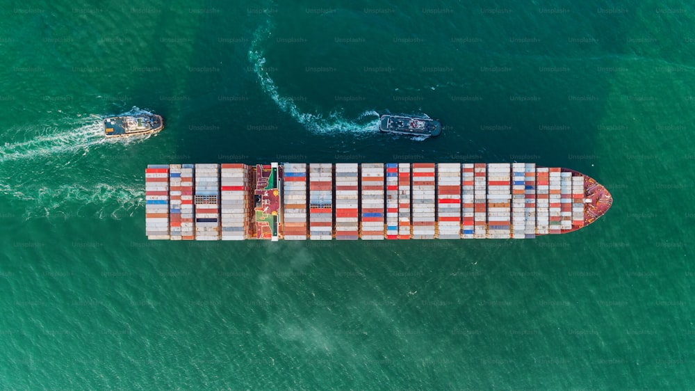 Aerial view Tug boats drag container ship to sea port for unloading container at crane bridge for logistics import  export or transportation concept background.