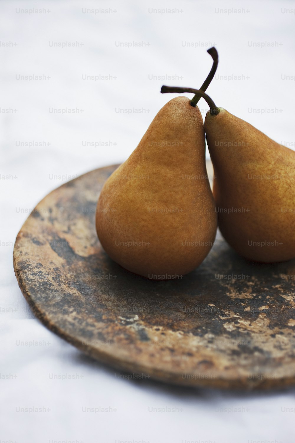 Dos peras sentadas en un plato sobre una mesa