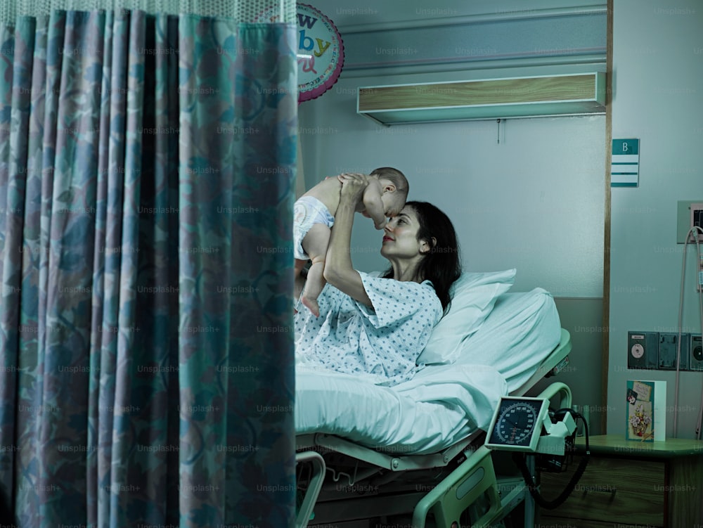 uma mulher segurando um bebê em uma cama de hospital