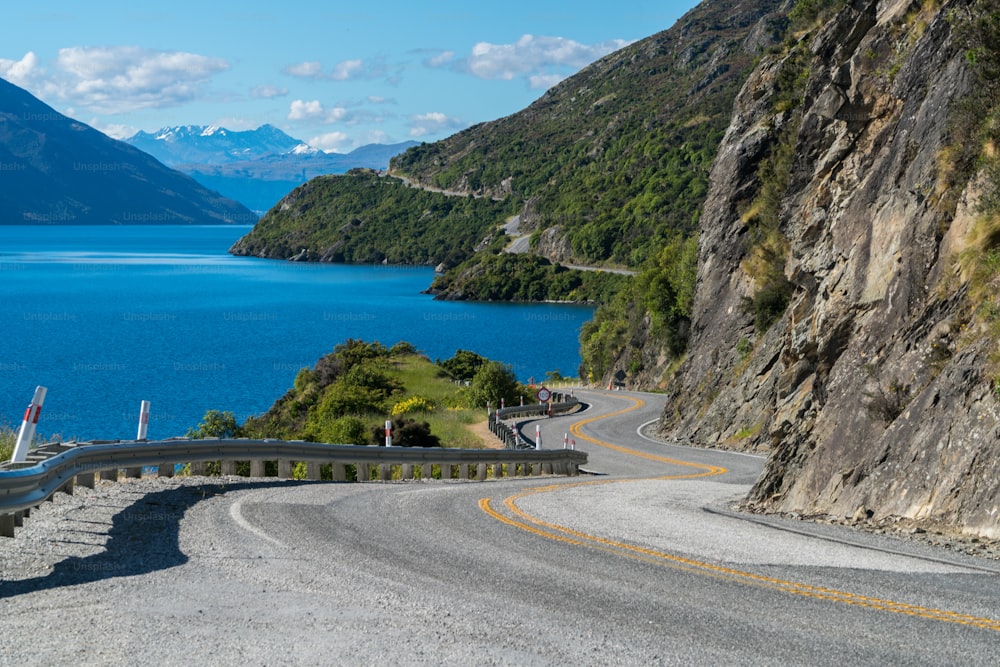 Carretera sinuosa a lo largo de acantilados montañosos y paisajes lacustres en Queenstown, Isla Sur de Nueva Zelanda. Viajes y road trip en verano.