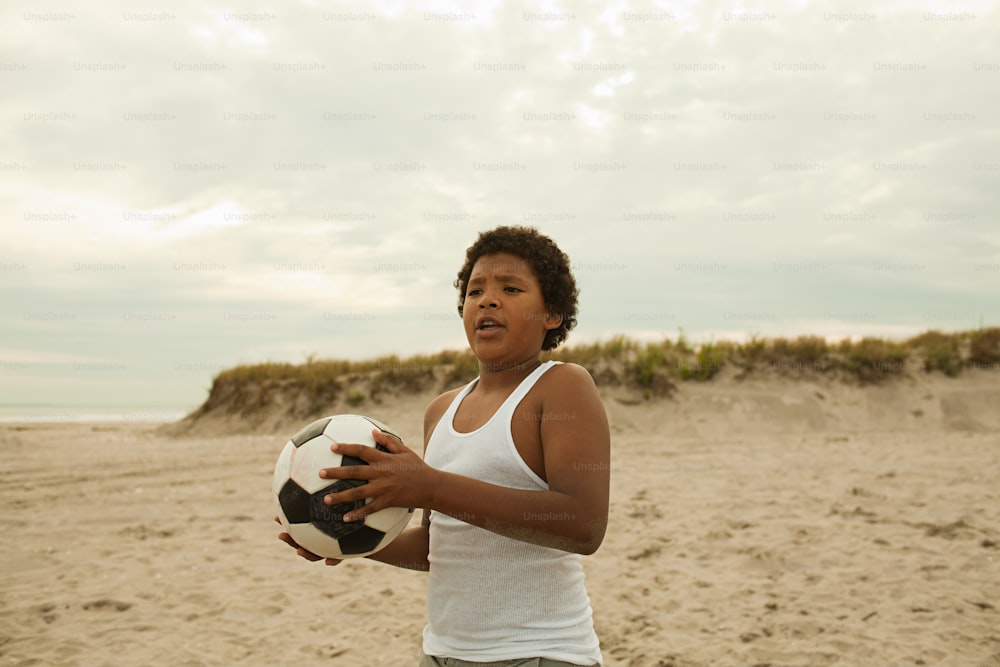 Una mujer sosteniendo una pelota de fútbol en una playa