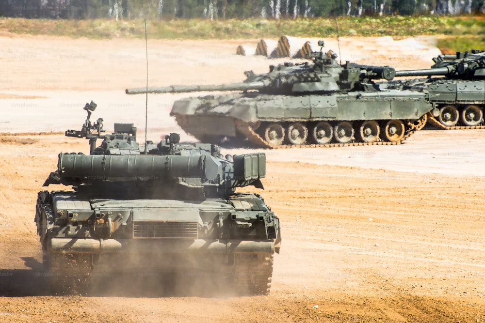 Military tank rides through the field, in the background two other tanks