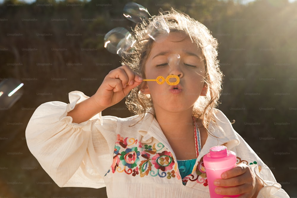 a little girl blowing bubbles on her nose