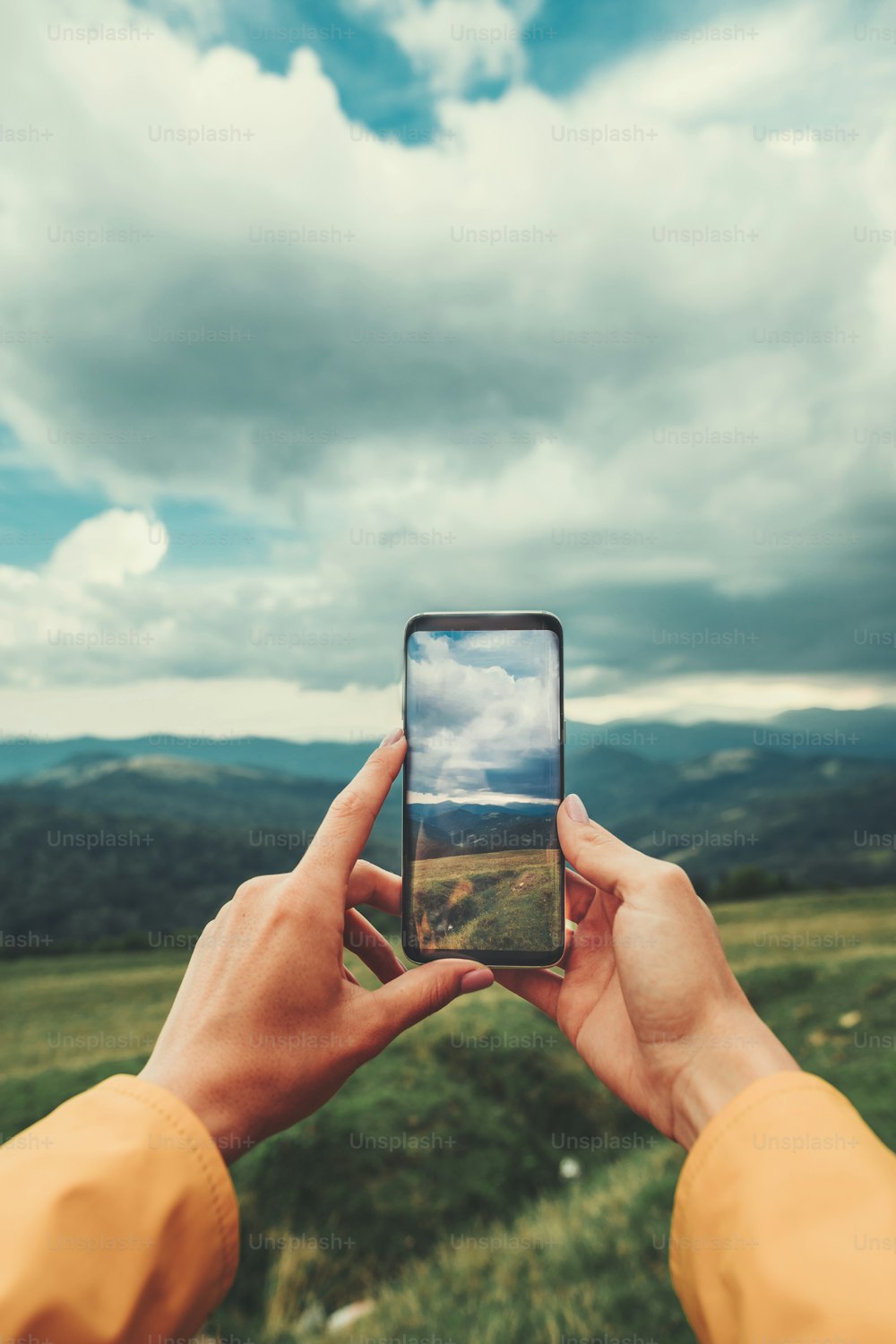 Primer plano de un teléfono inteligente moderno en manos de una viajera haciendo fotos y descansando en las montañas
