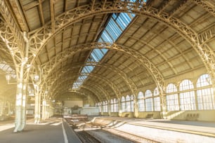 Architecture arcs incurvés, entretoises métalliques et toit en verre, détails intérieurs à la gare vide.
