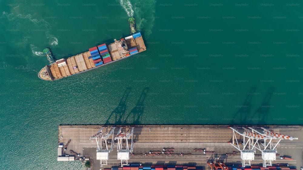 Aerial top view container ship at sea port and working crane bridge loading container for logistic, import export, shipping or transportation.