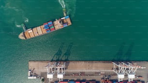 Aerial top view container ship at sea port and working crane bridge loading container for logistic, import export, shipping or transportation.
