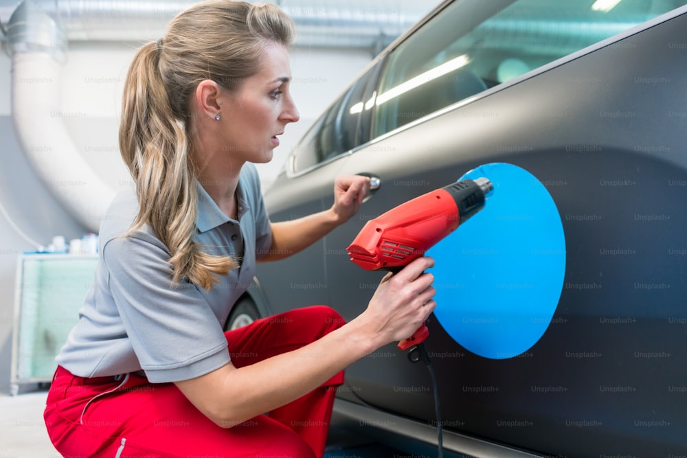 Woman putting promotional sticker with company slogan on a car