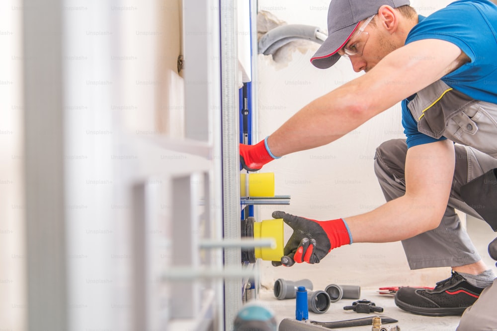 Caucasian Plumbing Worker Installing Toilet Bowl and Sanitary System Inside the House.