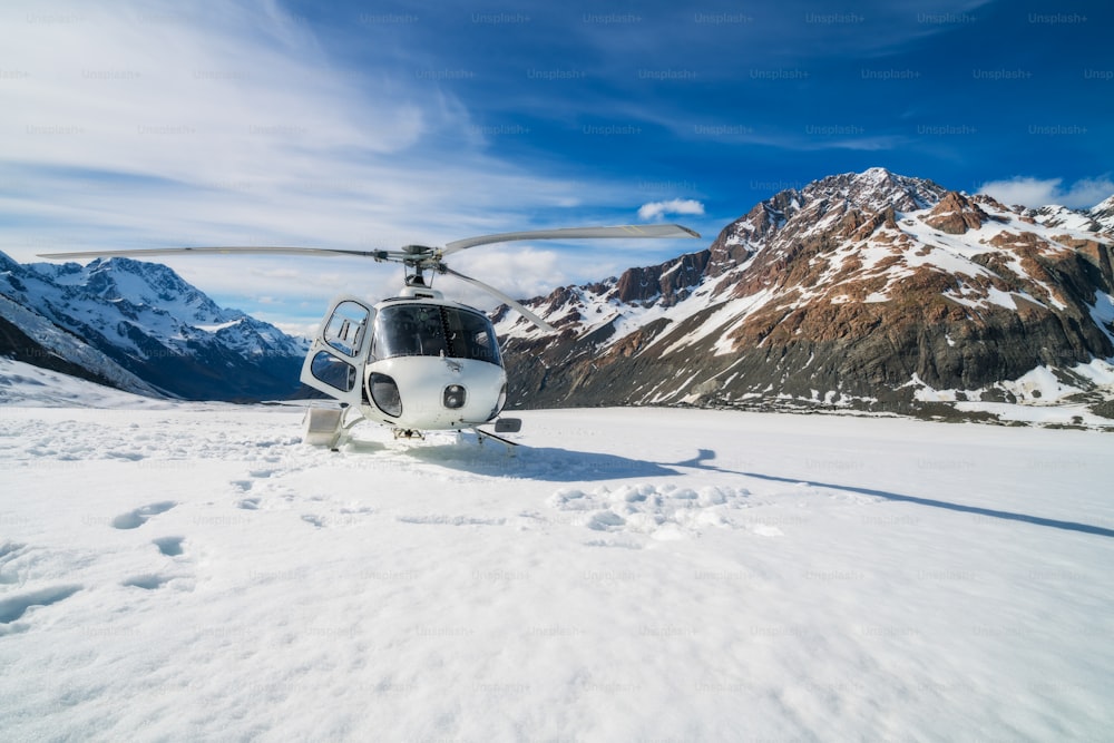 Helicóptero pousando na montanha de neve na geleira da Tasmânia em Mt Cook, Nova Zelândia. O serviço de helicóptero no Monte Cook oferece voos panorâmicos, pouso em geleiras e resgate de emergência.