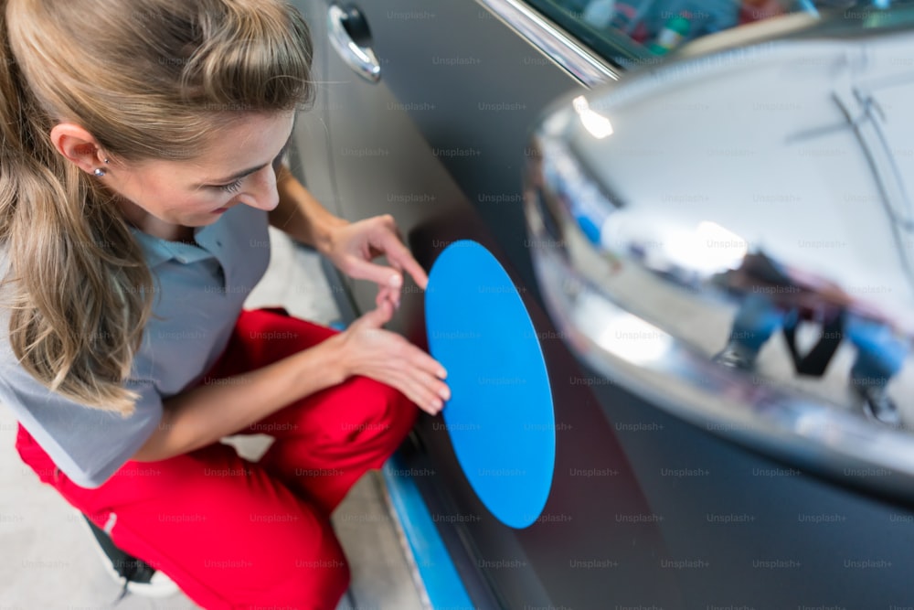 Woman putting promotional sticker with company slogan on a car