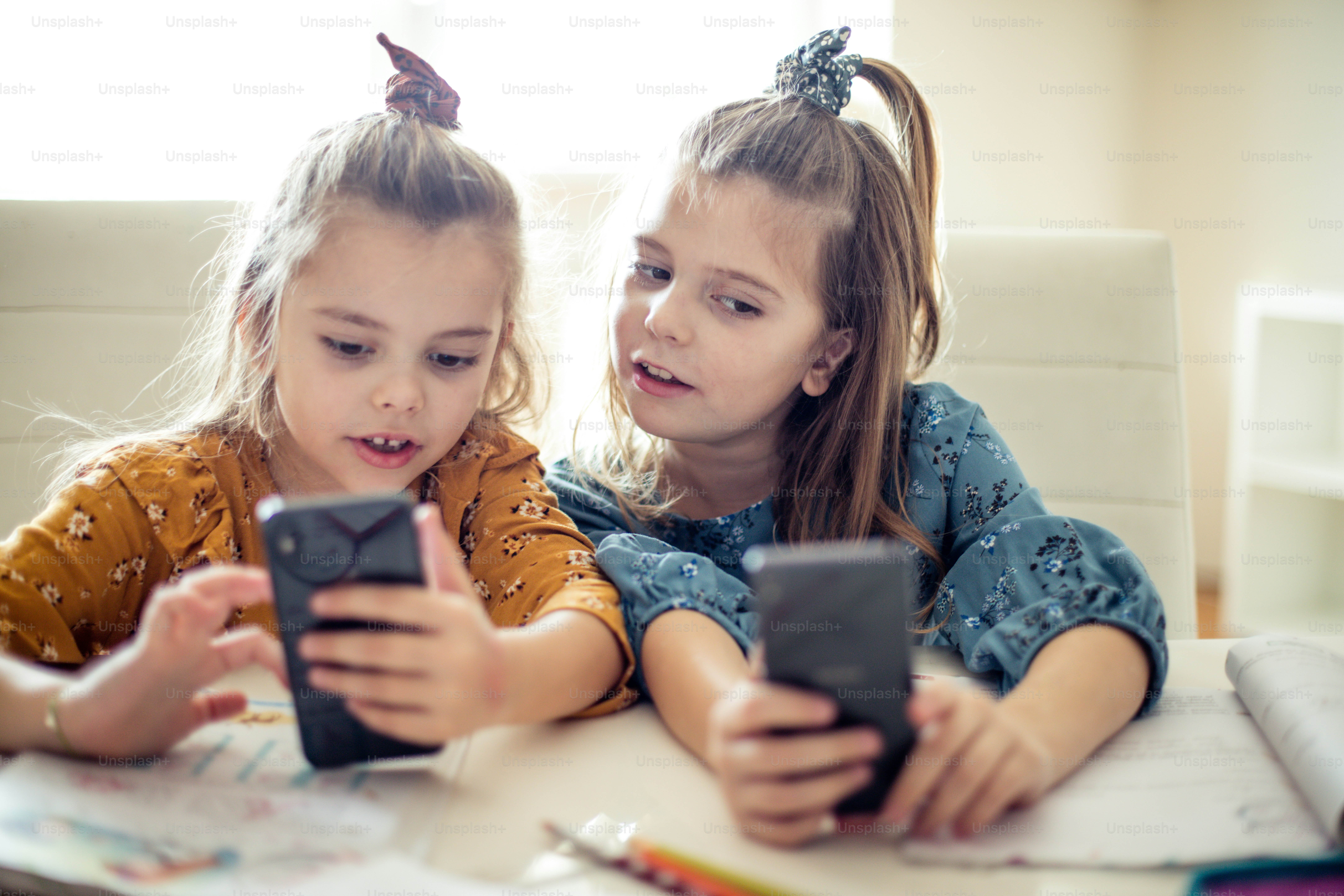 There are various games here. Two little school girls using smart phone.