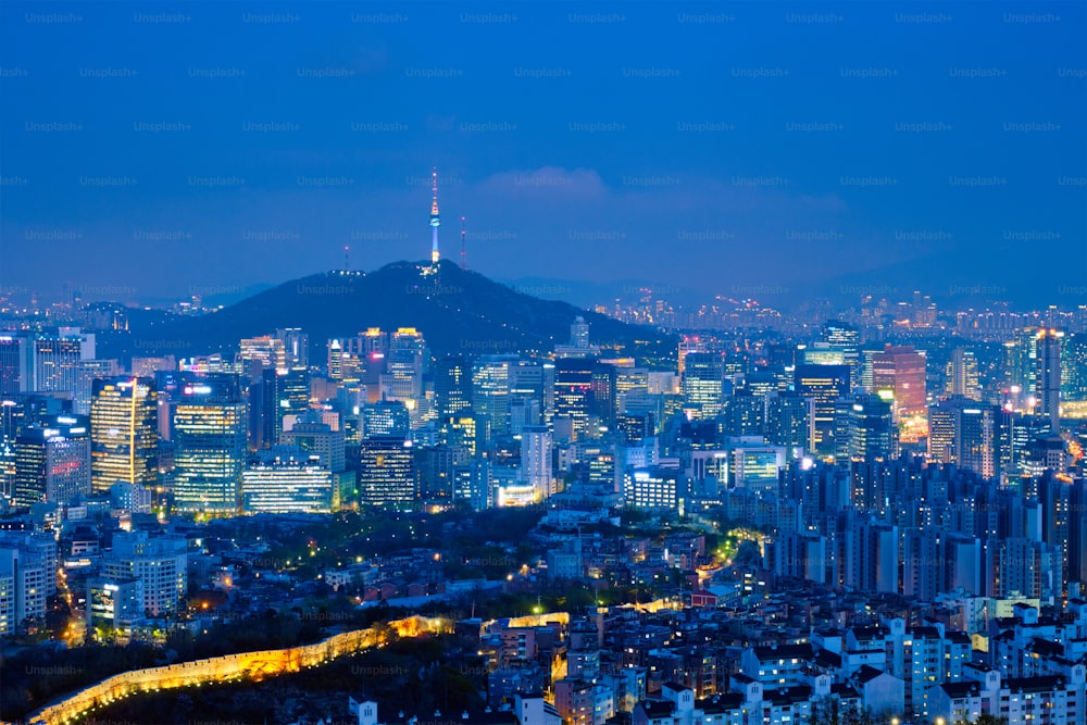 インワン山からの夕景に照らされたライトと南山ソウルタワーに照らされたソウルの繁華街並み。韓国、ソウル。