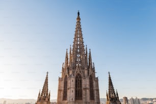 Torre della cattedrale gotica di Barcellona al crepuscolo contro un cielo azzurro limpido.