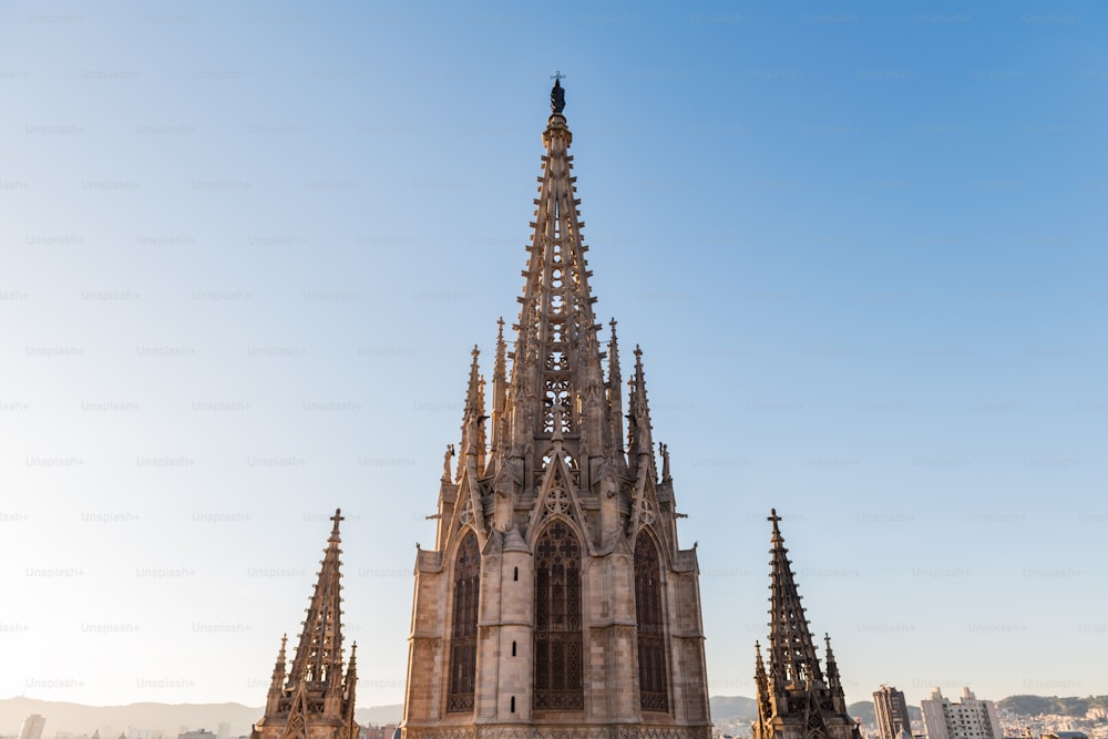 Tower of the gothic Cathedral of Barcelona at dusk against a clear blue sky.