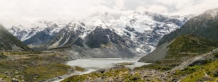 Montanhas, lagos e paisagem de prado no país de clima frio com neve e tempo nublado nas montanhas. A paisagem foi filmada em Mt Cook, Nova Zelândia, lugar famoso para trekking e ao ar livre.