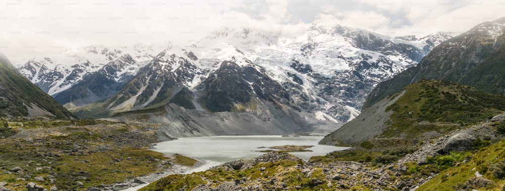 Berge, Seen und Wiesenlandschaft im kalten Klimaland mit Schnee und bewölktem Wetter auf den Bergen. Die Landschaft wurde in Mt Cook, Neuseeland, einem berühmten Ort für Trekking und Outdoor, aufgenommen.