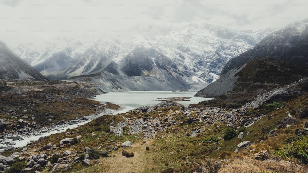 Montañas, lagos y paisajes de praderas en un país de clima frío con nieve y tiempo nublado en las montañas. El paisaje fue fotografiado en el monte Cook, Nueva Zelanda, lugar famoso por el senderismo y las actividades al aire libre.